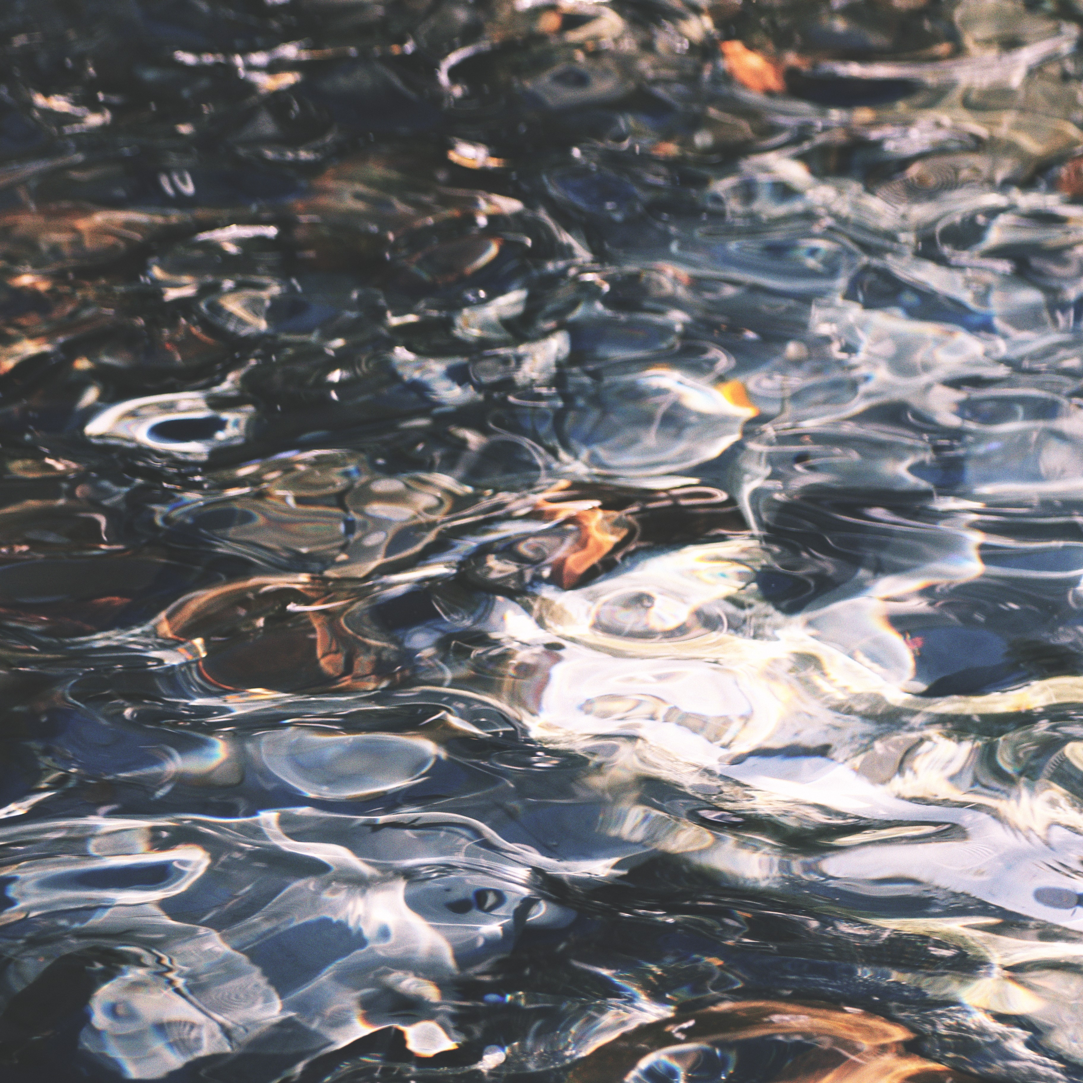 rippling water with vibrant brown stones underneath